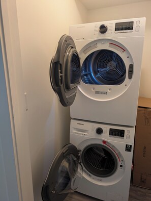 A stacked washer and dryer unit with a digital control panel, a moisture sensor, and a digital inverter label.