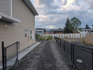 A residential area with houses, a fenced yard, and a gravel path.