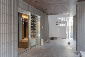 Un pasillo con suelo de baldosas y una puerta de vidrio que da a una habitación.
