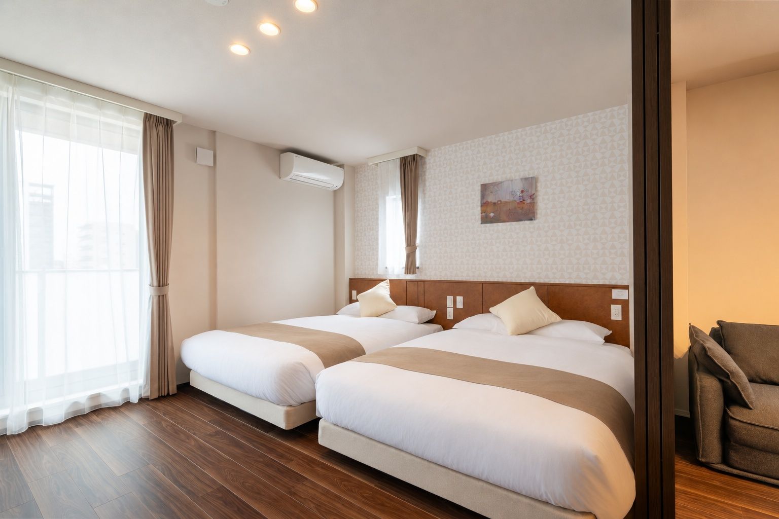 A hotel room with two beds, a large window with curtains, an air conditioning unit, and a painting on the wall.