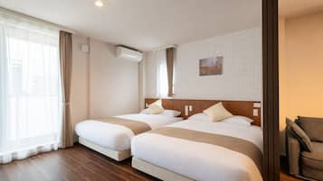 A hotel room with two beds, a large window with curtains, an air conditioning unit, and a painting on the wall.