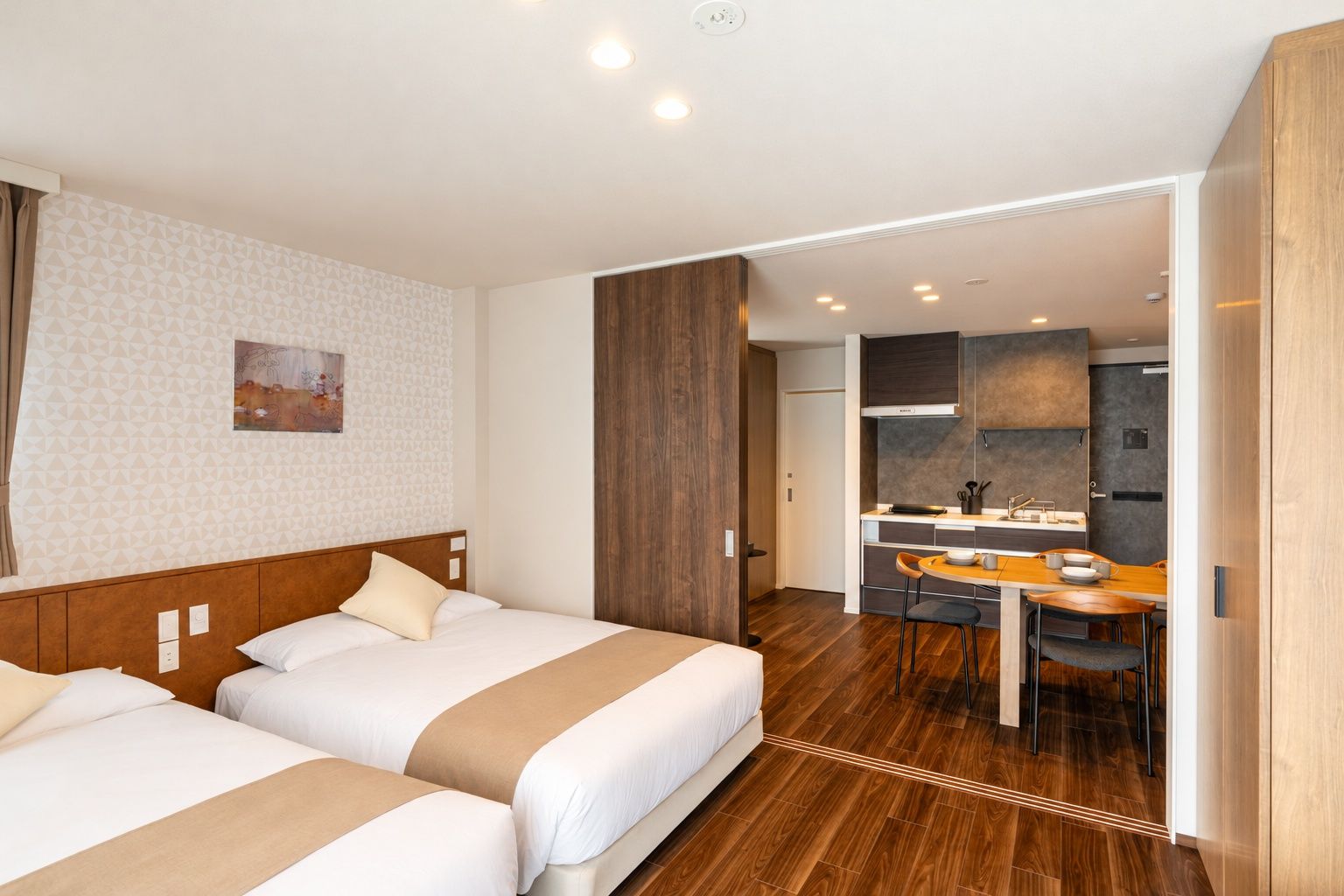 Una habitación de hotel con dos camas, un área de comedor y una kitchenette.