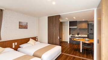 Una habitación de hotel con dos camas, un área de comedor y una kitchenette.