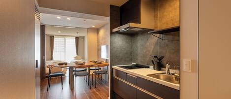A modern kitchen with a built-in stove, a sink, and a dining area with a table and chairs.
