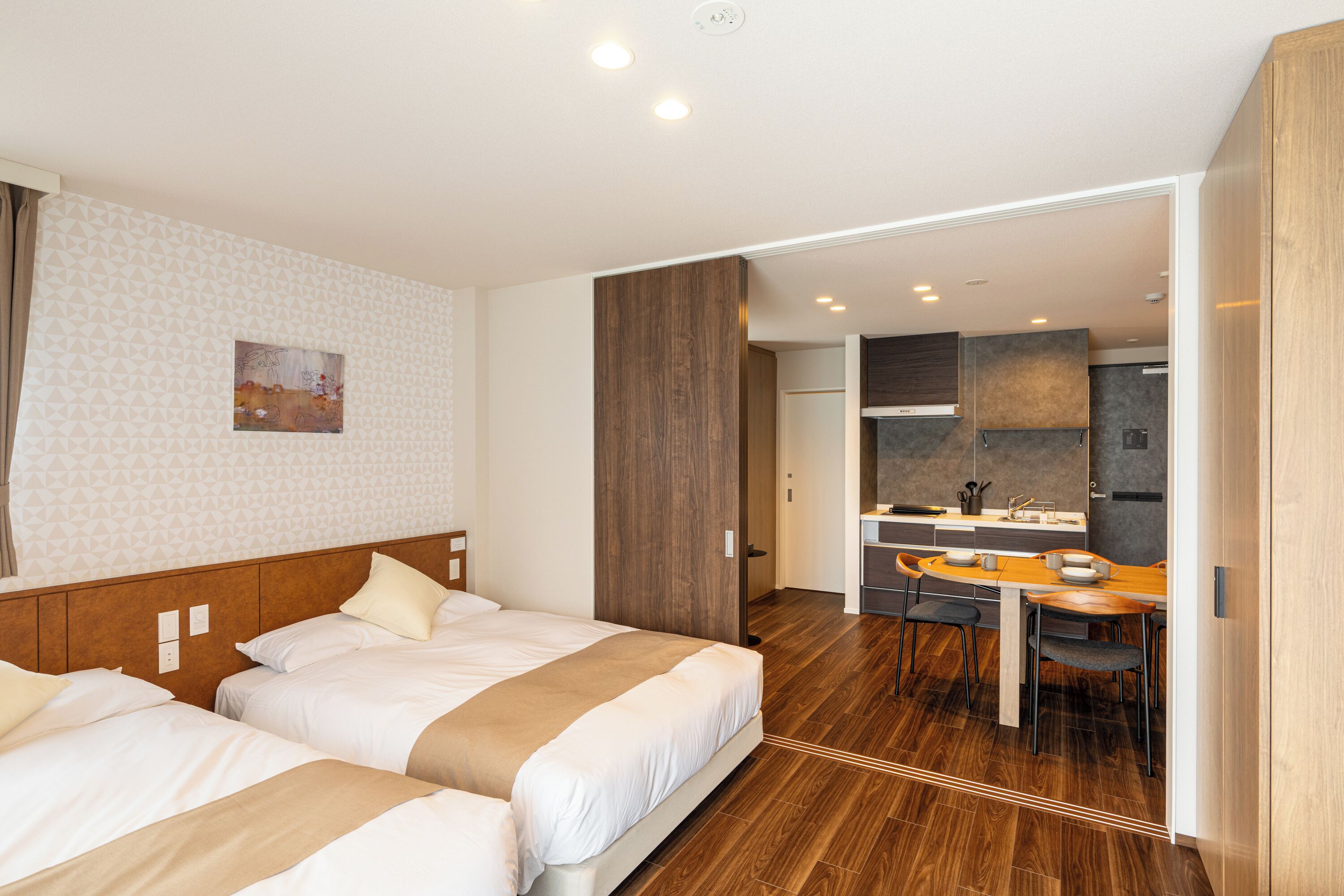 Ein Hotelzimmer mit zwei Betten, einer Küchenzeile und einem Essbereich.