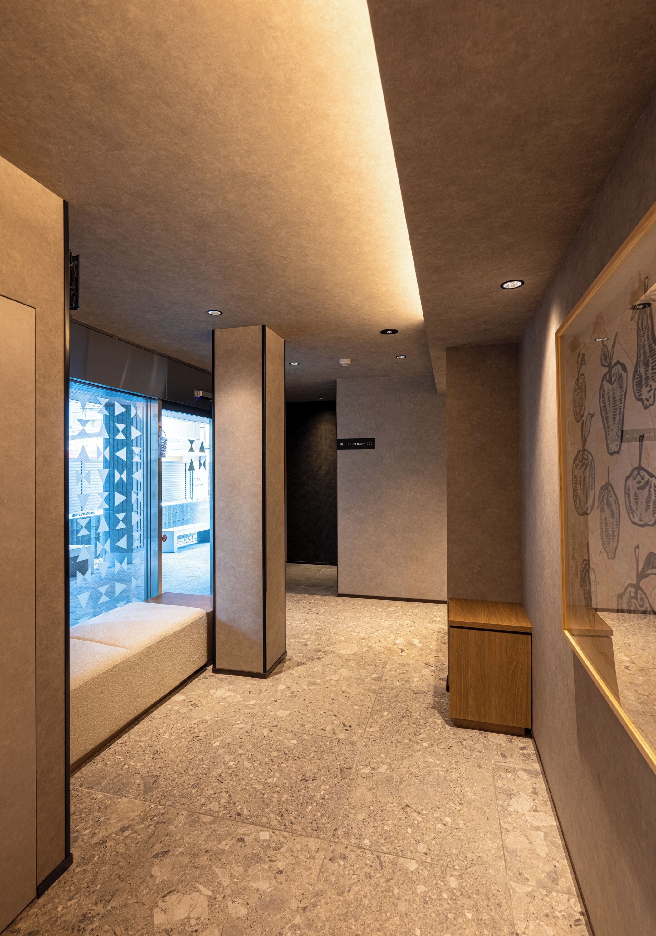 A modern hotel corridor with a marble floor, a wooden bench, and a wall with a botanical print.
