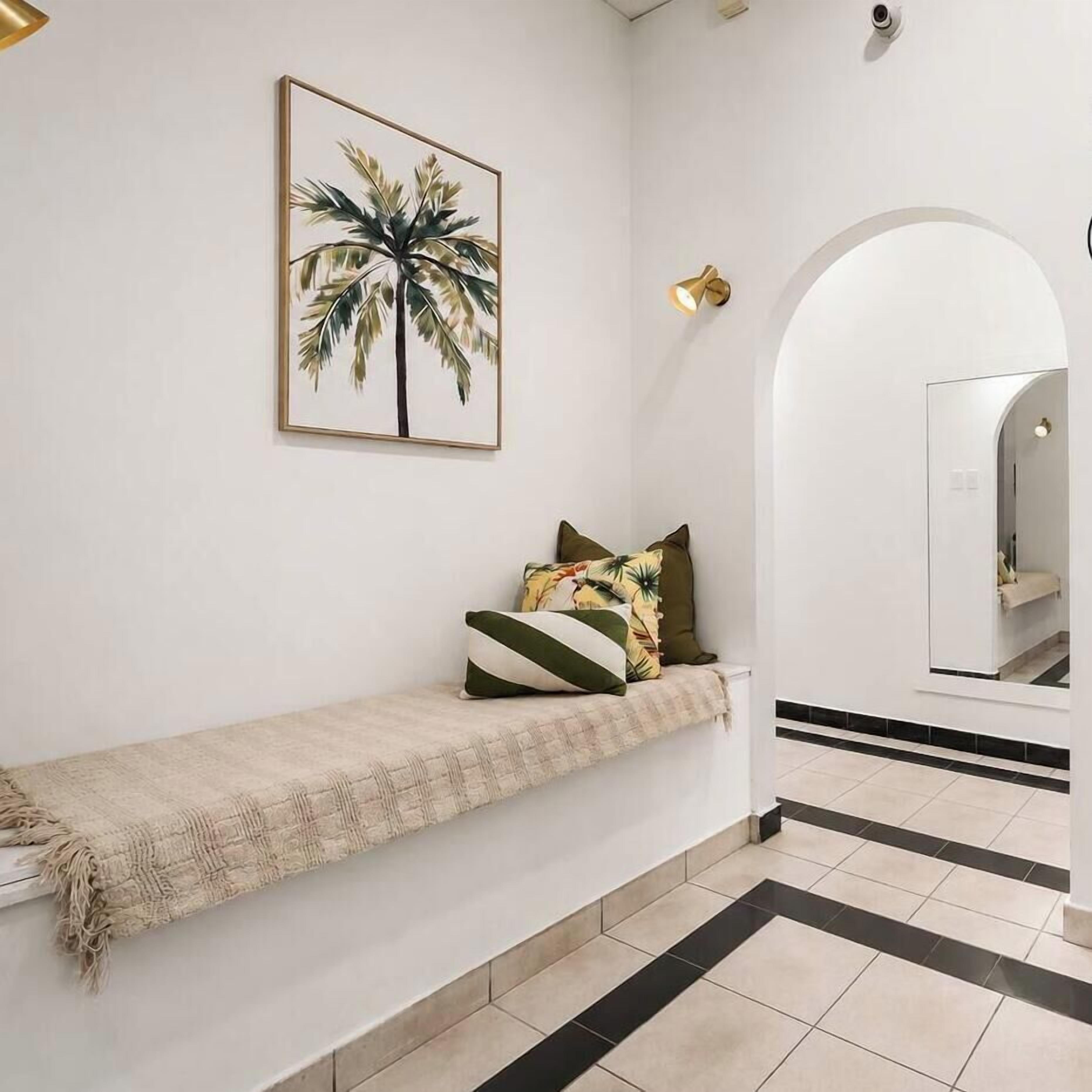 A hallway with a bench, a potted plant, and a mirror.