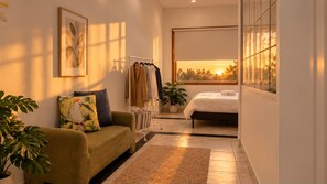 A modern bedroom with a bed, a bedside table, a window with a view, a wardrobe, and a plant.