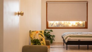 A bedroom with a bed, a window with a view, a door, and a chair.
