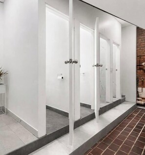 Un baño moderno con paredes blancas, piso de baldosas y una pared decorativa de ladrillo.