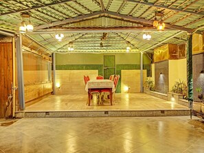 An indoor dining area with a table set for four, a tiled floor, and a green wall with a door. - Super Deluxe Room Hotel Vihaan Residency (Dera Bassi)
