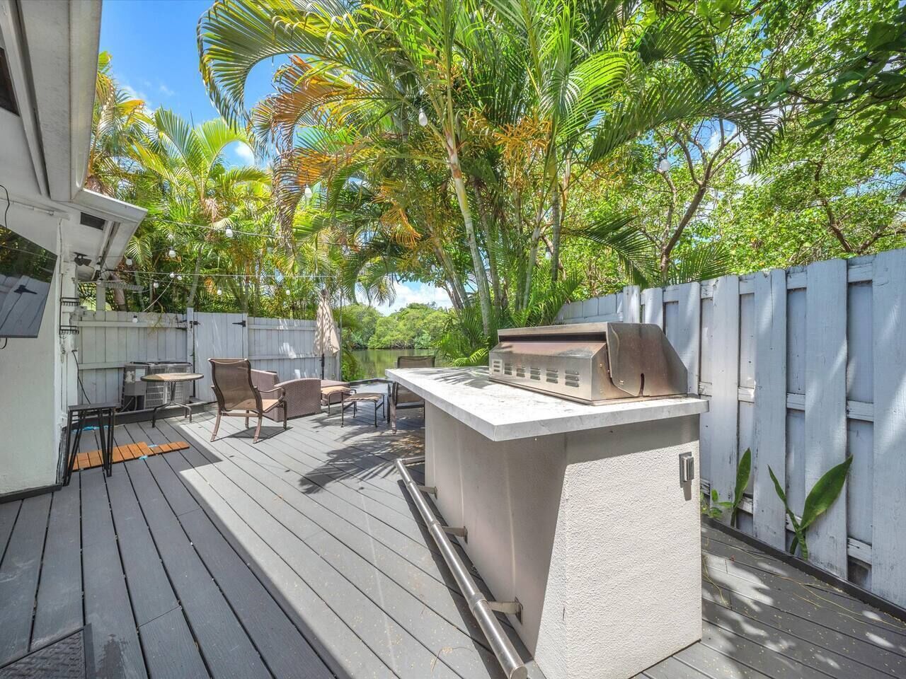 An outdoor deck with a barbecue grill, seating area, and a view of a lake.