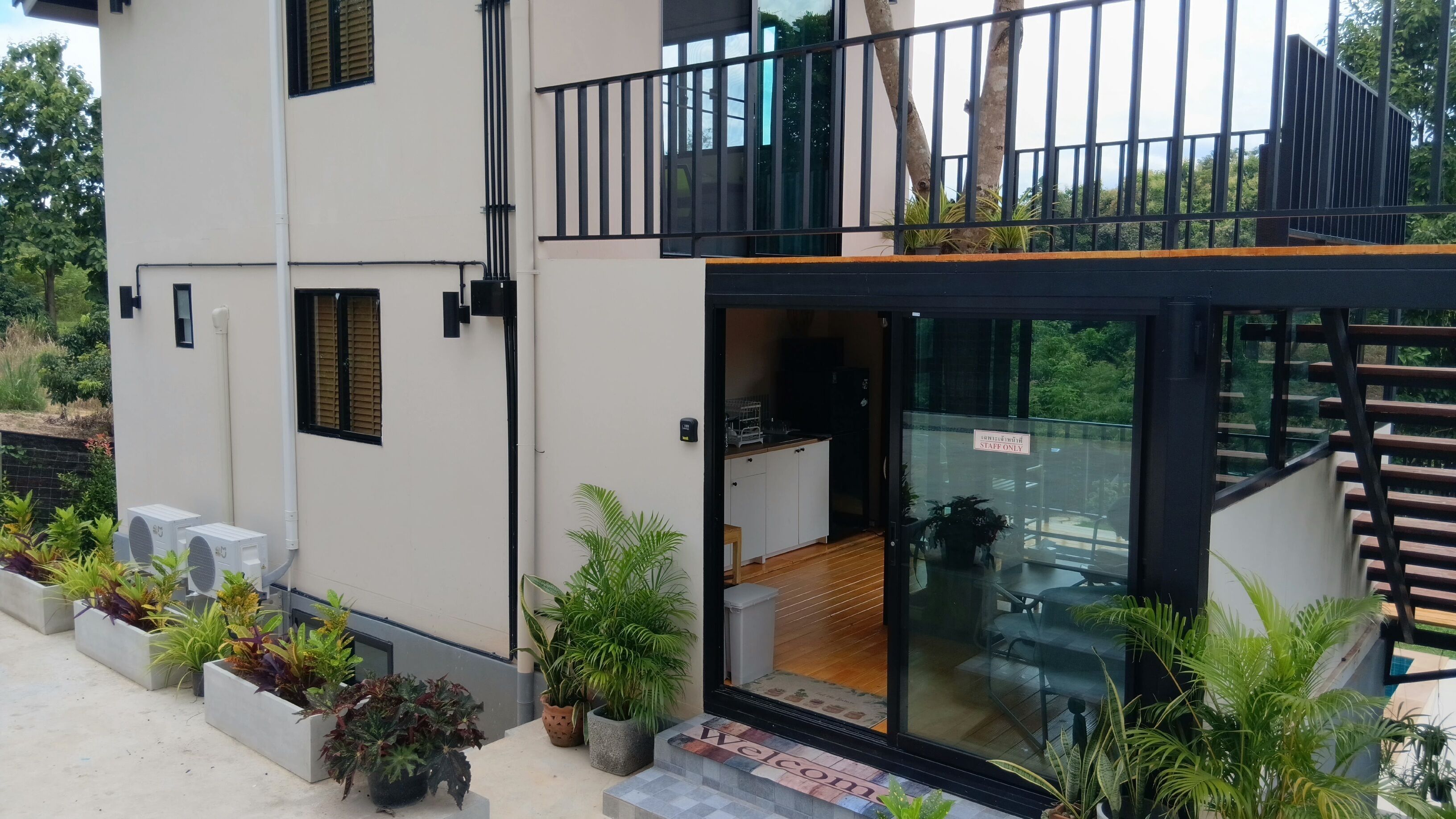 A modern building with a glass entrance, a balcony, and a sign indicating it's staff-only.