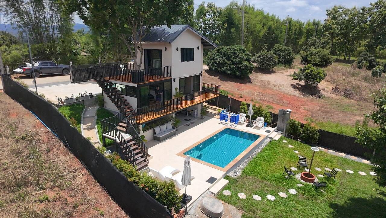 A two-story house with a balcony, a swimming pool, and a fenced yard.