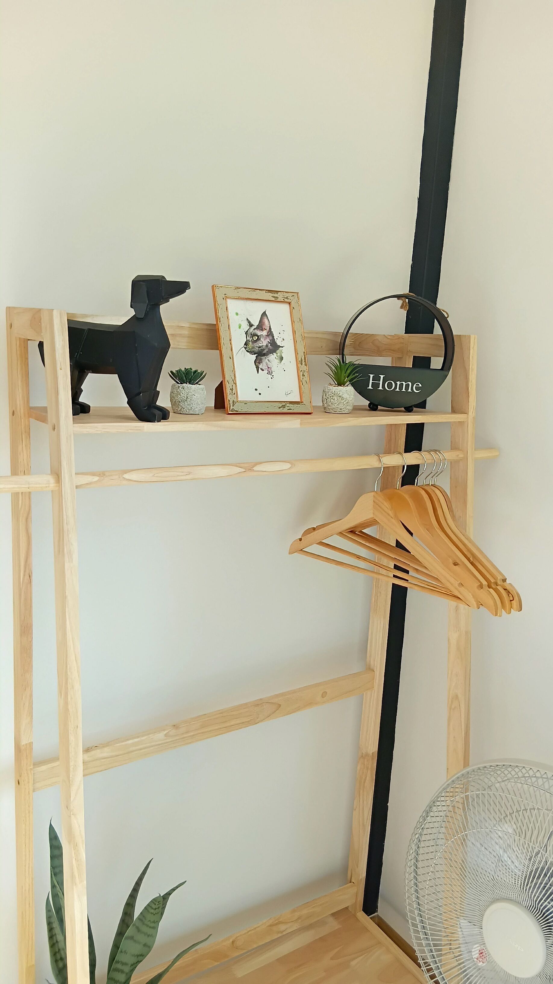 A wooden shelf with a black dog figurine, a framed picture, and a basket labeled 'Home'.