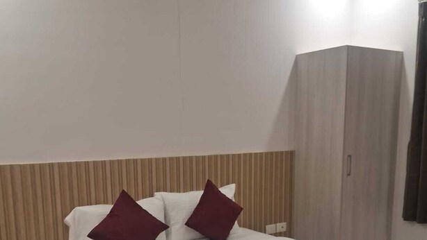 Een hotelkamer met een bed, nachtkastje, kledingkast en gordijn.
