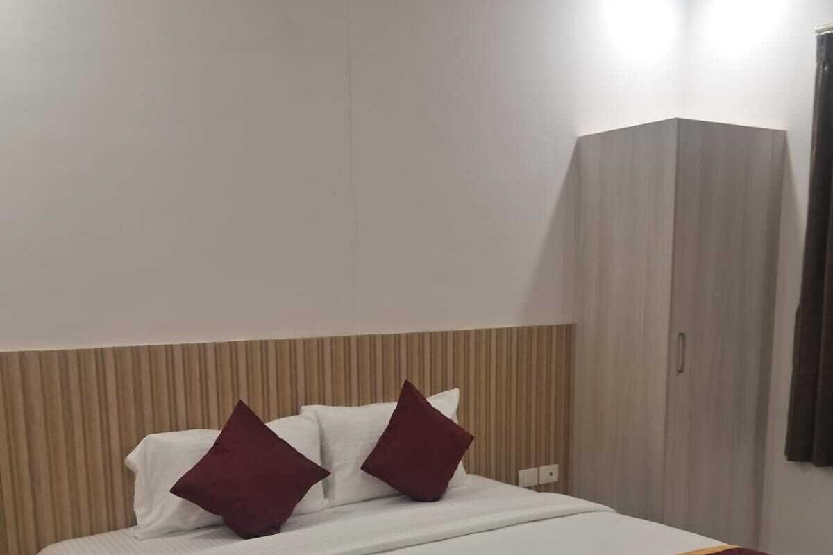 A hotel room with a bed, a nightstand, a wardrobe, and a curtain.