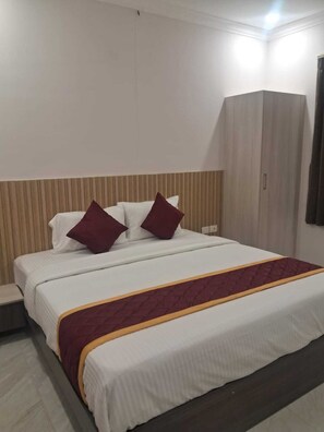 Una habitación de hotel con cama, mesita de noche, armario y cortina.