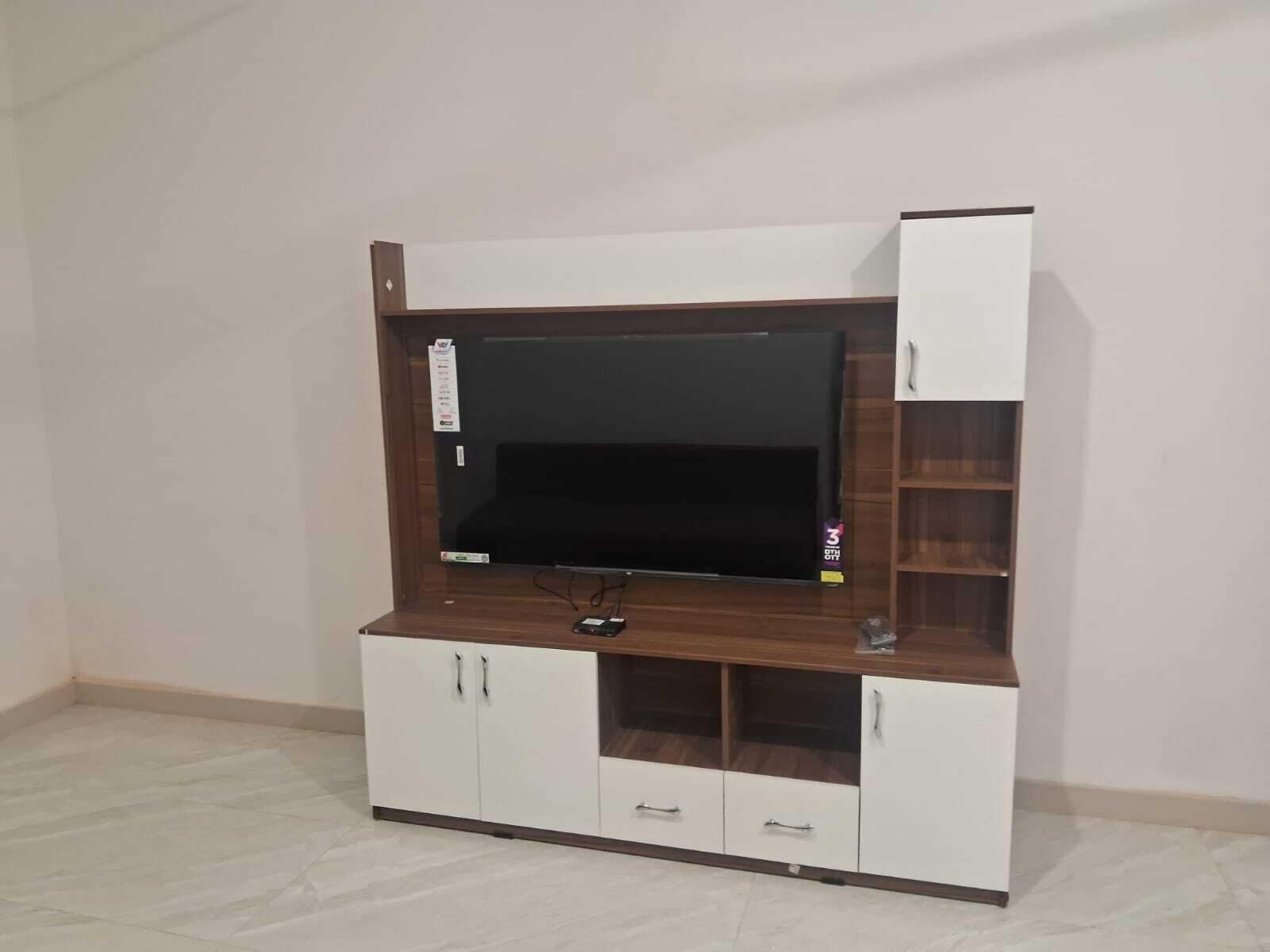 Un meuble pour télévision avec un téléviseur à écran plat, plusieurs placards de rangement et une étagère.