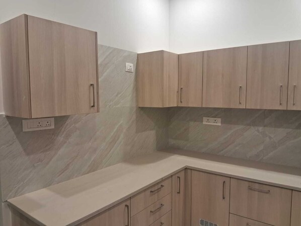 A kitchen with wooden cabinets and a marble backsplash.