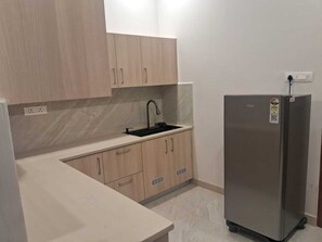 A kitchen with light wood cabinets, a stainless steel refrigerator, and a black faucet. - 7th Stay - Karaikudi (Karaikudi)