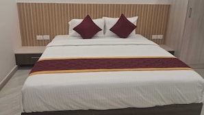 Een hotelkamer met een bed, hoofdeinde en nachtkastje.