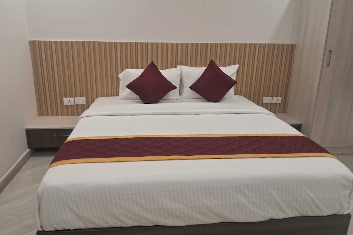 A hotel room with a bed, a headboard, and a bedside table.