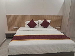 A hotel room with a bed, a headboard, and a bedside table. - 7th Stay - Karaikudi (Karaikudi)