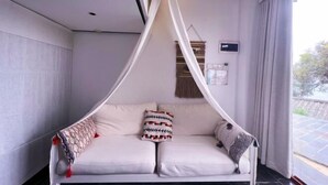 Habitación con cama con dosel, panel de control en la pared y vistas al exterior.