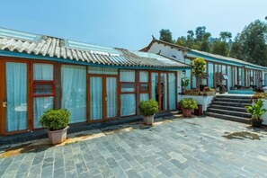 A traditional building with a tiled roof, large windows, and potted plants.