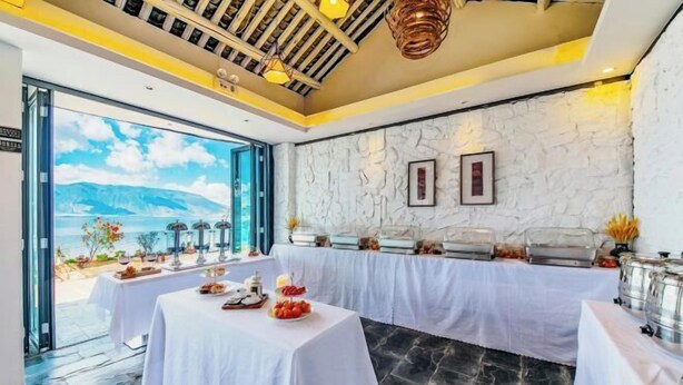 Un comedor con una mesa larga dispuesta para una comida, vista al exterior y una pared de piedra con cuadros enmarcados.