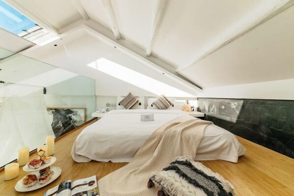 A modern bedroom with a large bed, a glass ceiling, and a view of the sky.