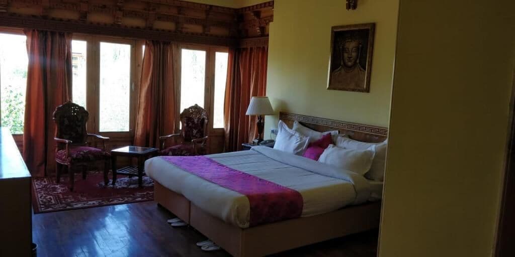 Une chambre d’hôtel avec un lit, un bureau, une chaise et une fenêtre avec des rideaux.