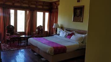 A hotel room with a bed, a desk, a chair, and a window with curtains.