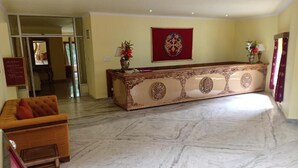 A reception area with a marble floor, a reception desk, a sofa, and a framed artwork on the wall. - The Druk Ladakh (Leh)