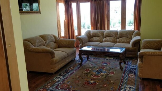 A living room with a sofa set, a coffee table, and a patterned rug. - The Druk Ladakh (Leh)