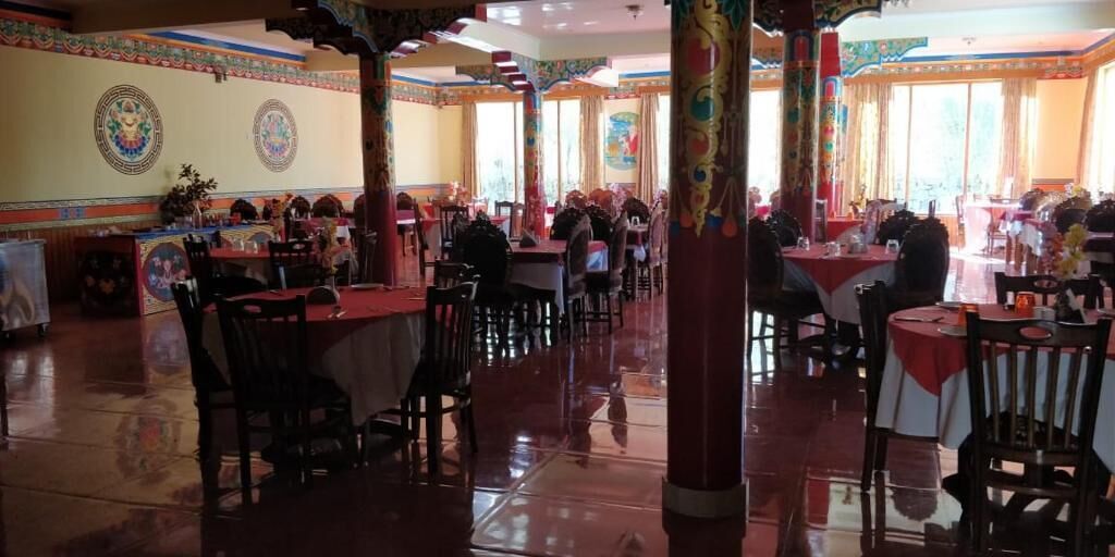 A restaurant with multiple tables and chairs, a polished floor, and decorative wall art.