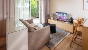 A modern living room with a sofa, a TV, a cabinet, and a dining area.