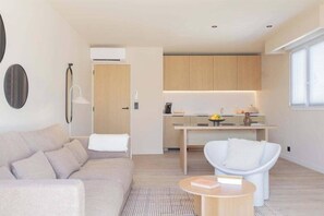 A modern living room with a sofa, a round coffee table, and a dining area with a table and chairs.