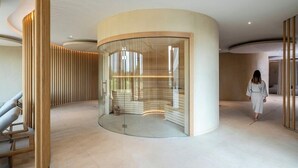 A modern interior with a curved glass wall, a wooden column, and a person walking.