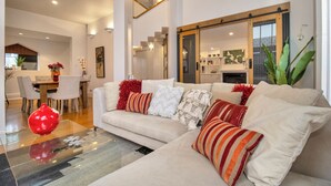 Ein modernes Wohnzimmer mit einer Couch, einem Essbereich und einer Küche im Hintergrund.