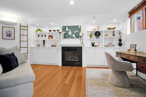 Un salon moderne avec une cheminée, des meubles blancs et un canapé gris.