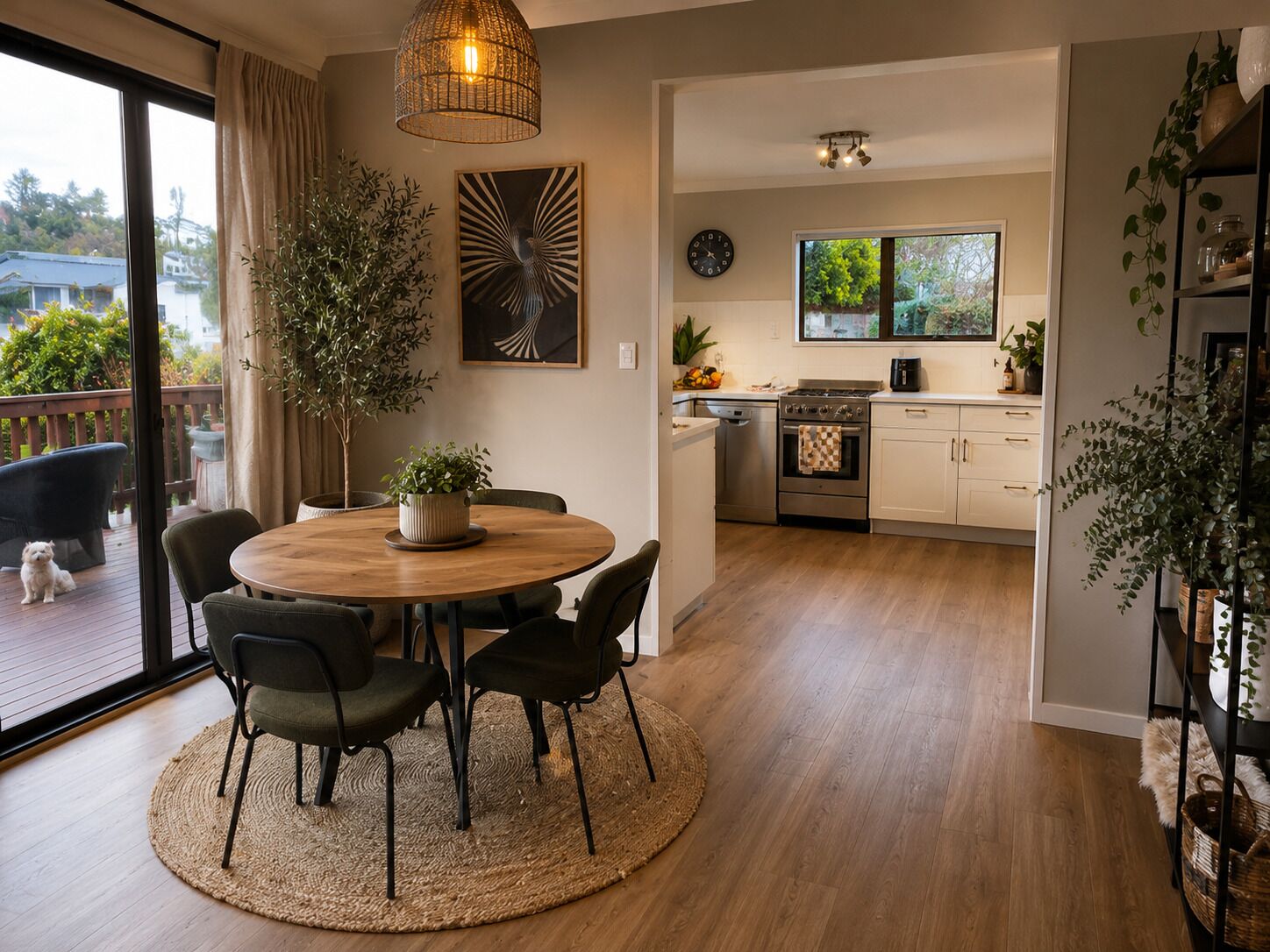 A modern kitchen with a dining area, wooden flooring, and a view of the outdoors.