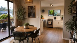 A modern kitchen with a dining area, wooden flooring, and a view of the outdoors. - A-frame with pool (Cambridge)