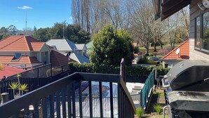 A wooden deck with a grill and a view of houses and trees. - A-frame with pool (Cambridge)