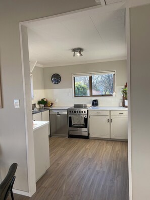Eine moderne Küche mit weißen Schränken, einem Edelstahlbackofen und einem Fenster mit Blick auf Bäume.
