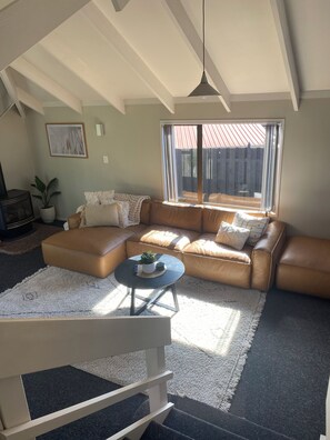 Ein Wohnzimmer mit Ecksofa, Couchtisch und großem Fenster mit Blick.