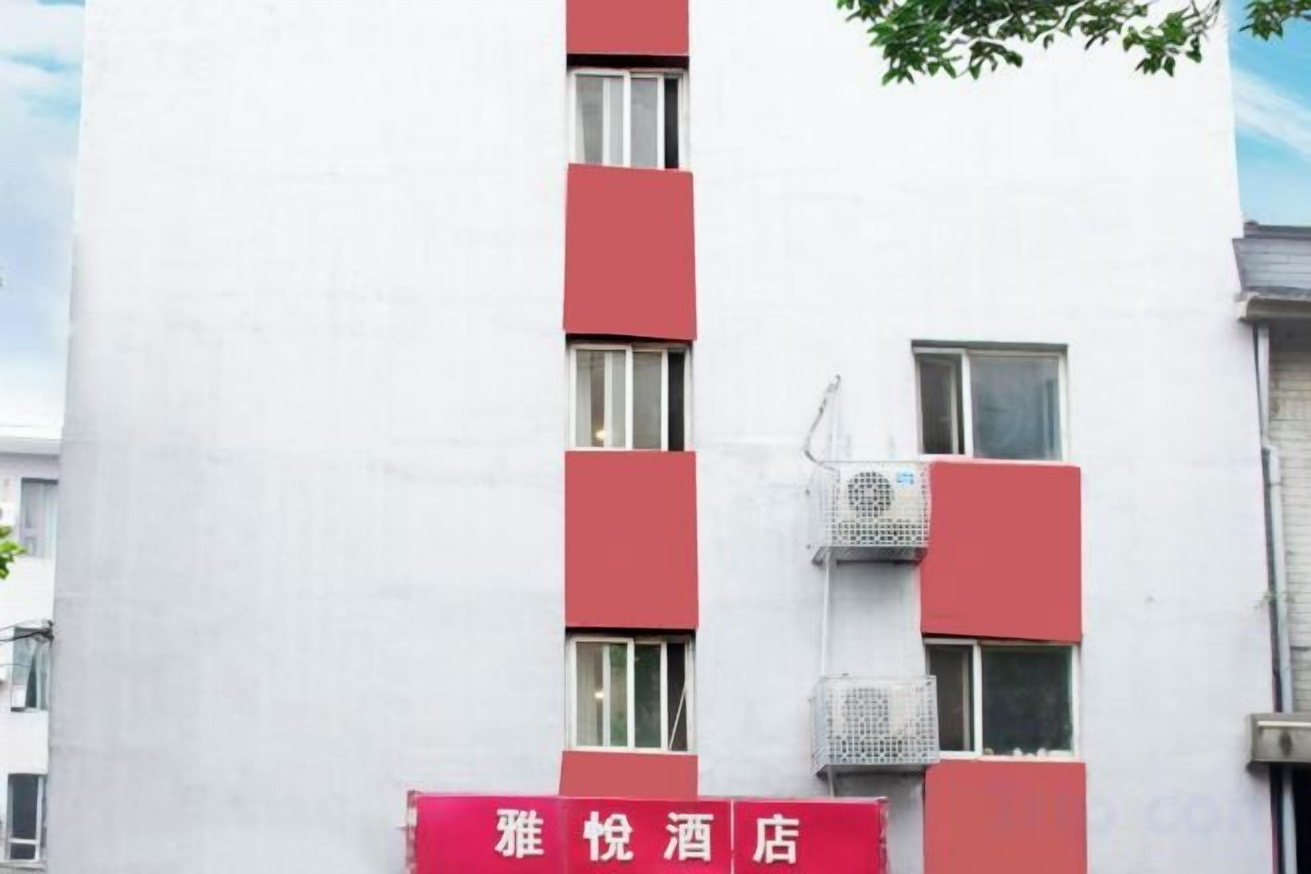 Un bâtiment à la façade rouge et blanche, doté de nombreuses fenêtres et d’une enseigne indiquant qu’il s’agit d’un hôtel.