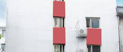A building with a red and white facade, multiple windows, and a sign indicating a hotel.