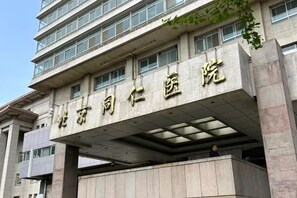 A building with a large sign in Chinese characters, a covered entrance, and a person visible inside. - Joyinn Hotel (Beijing Tongren Hospital Chong Wen Men Subway Station ) (Beijing)